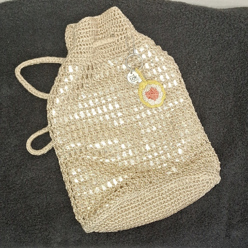 The Sak Crochet Drawstring Backpack in Natural Beige with Yellow & Coral Charm
